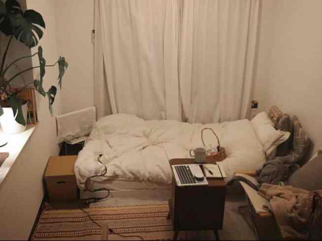 白とナチュラルな色調の小さなワンルームの寝室、ベッドとキリムラグが配置された雰囲気のあるインテリア