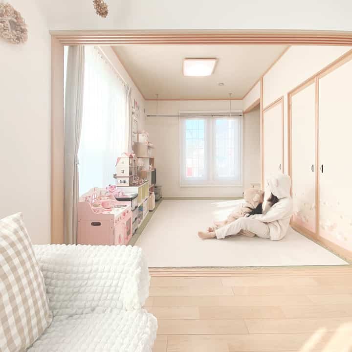 Bright natural-toned multipurpose room featuring kids sitting on a white rug and a toy kitchen set placed near the window