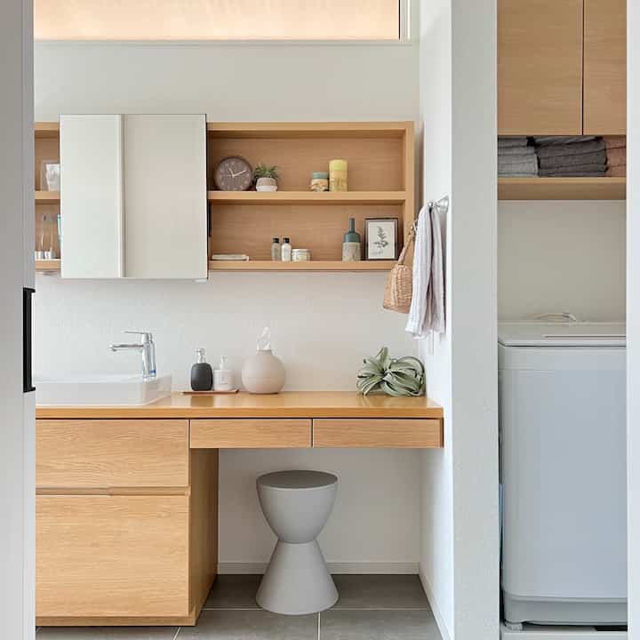 Bright white and warm wood-tone laundry and bathroom space featuring clean storage and simple, efficient design