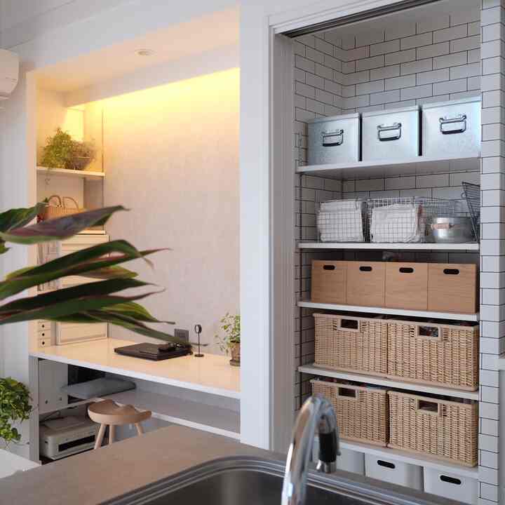 白とナチュラルカラーのキッチンスペース、棚とデスクが配置された清潔感と温かみのあるインテリア