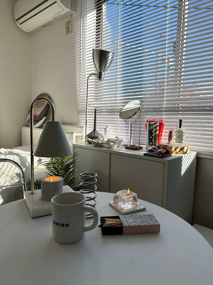Bright white-toned living room featuring a round table with a coffee mug and candles creating a cozy atmosphere