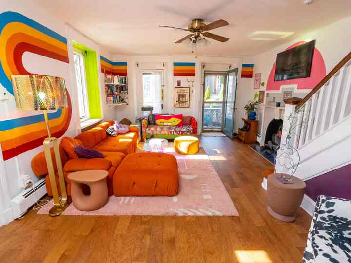 Bright and cozy living room with orange sofa and retro wall design creating vibrant atmosphere