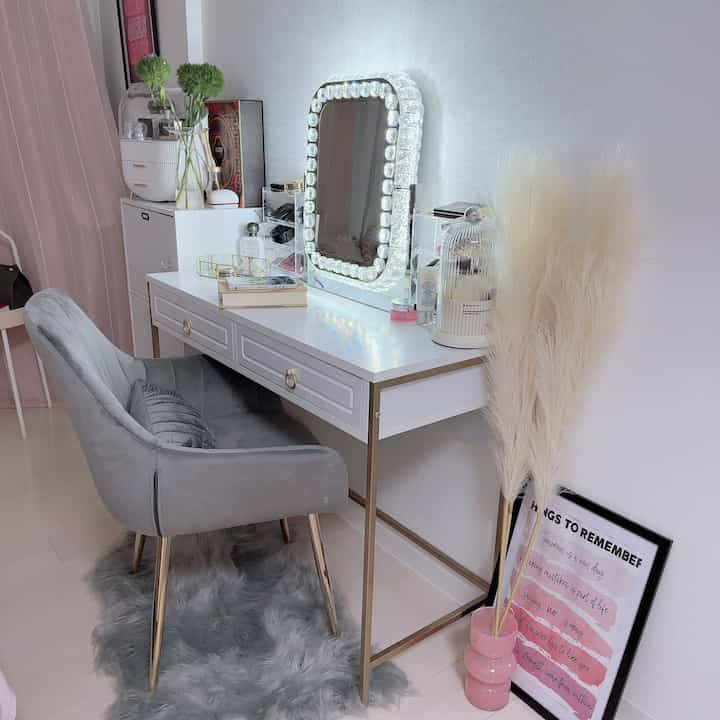 白とグレーのトーンのドレッサー周り、ゴールド脚のチェストとベルベットチェアが配置された雰囲気のあるインテリア