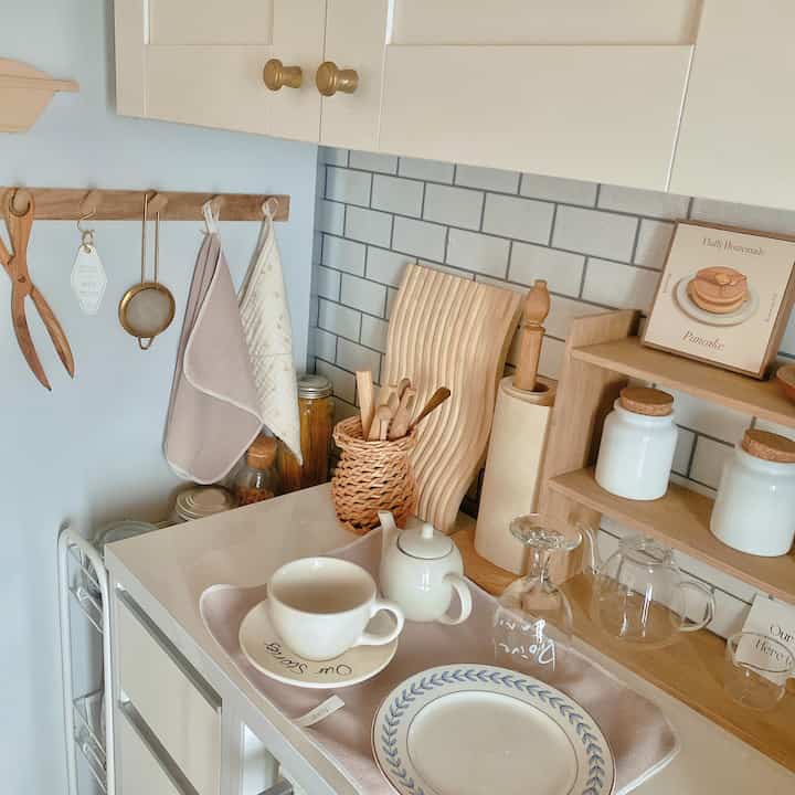 Beige and white toned kitchen featuring dishes and wooden utensils arranged neatly, creating a natural and cozy atmosphere