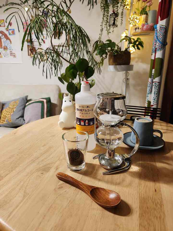 Natural wood tone dining space featuring a round table with mini siphon and coffee items, creating a cozy home cafe atmosphere