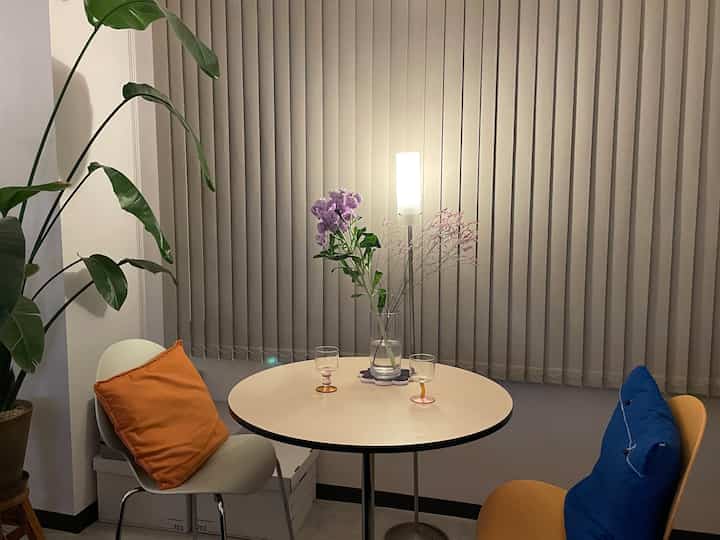 温かみのあるブラウンとホワイトの色調の円形の部屋、ミッドセンチュリーモダンスタイルの丸テーブルと二脚の椅子が配置された雰囲気のあるおうちカフェ空間