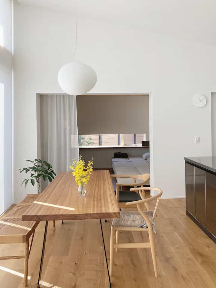 ナチュラルカラーのダイニング、木製のテーブルと椅子、レースカーテン、低い天井が印象的な雰囲気のあるインテリア