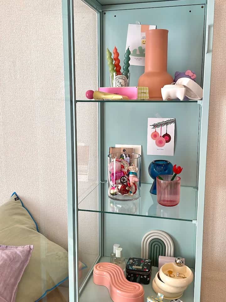 パステル調で透明なガラス棚があるシンプルなリビングのオブジェディスプレイ