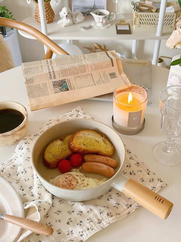White and natural-tone kitchen featuring frying pan and candle with cozy home cafe atmosphere