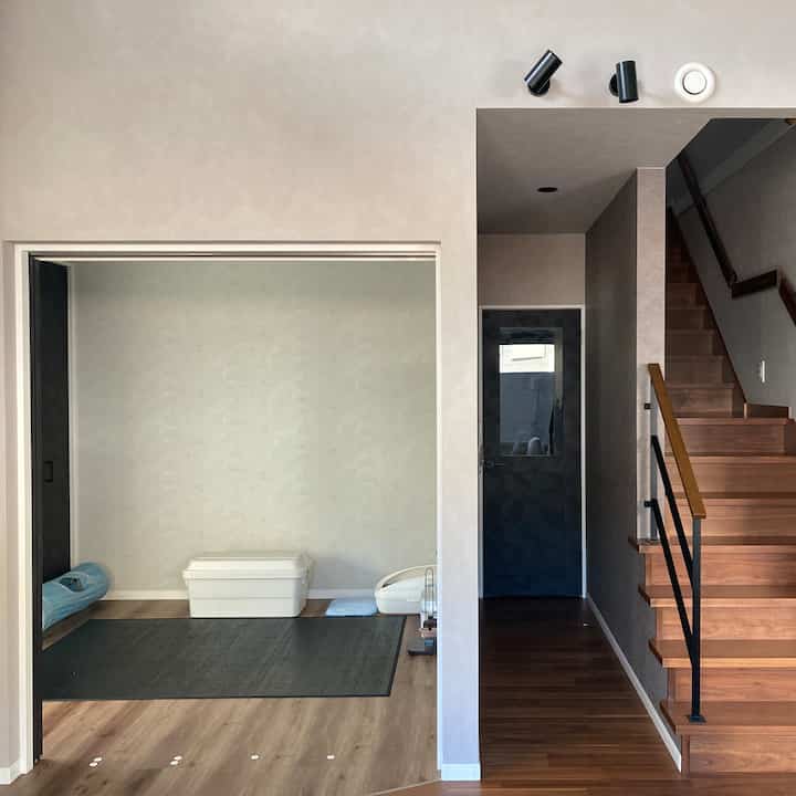Natural tone small cat room featuring pet supplies and wooden staircase with neat, minimalist atmosphere