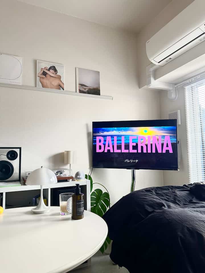 White and black toned studio apartment living room featuring a TV and table lamp with a simple modern vibe