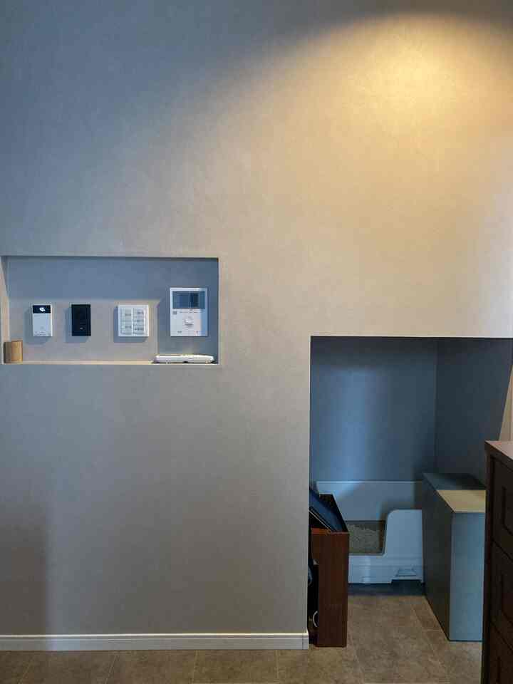 ナチュラルなベージュとグレーの壁にリモコンとスイッチ用の小さな隙間収納が配置されたシンプルで落ち着いたインテリア