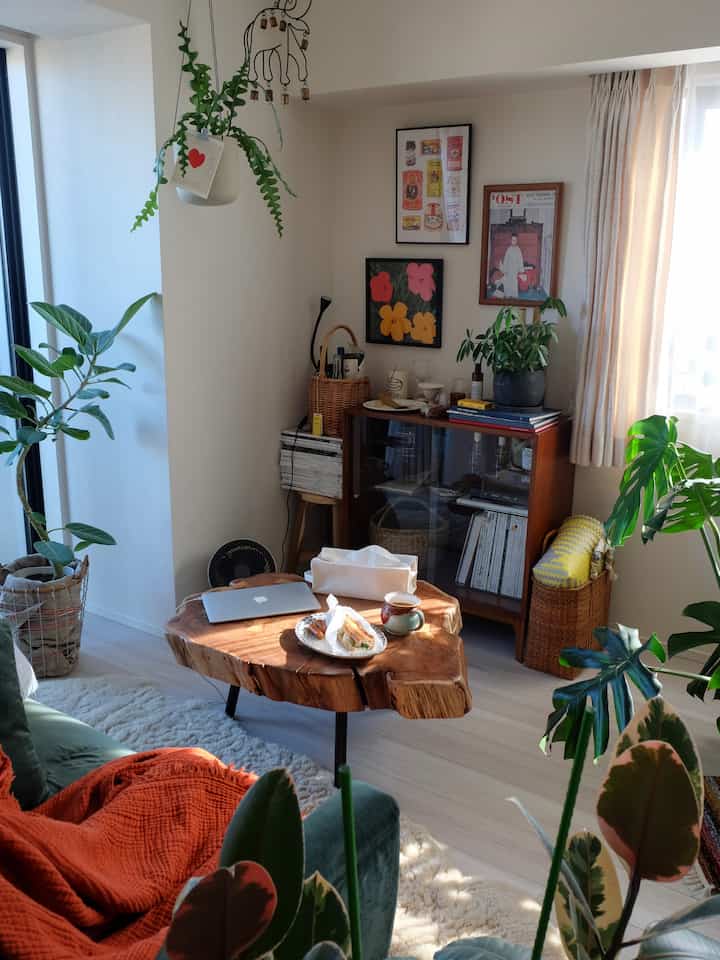 Bright natural-toned living room featuring a wooden coffee table and lush indoor plants creating a cozy interior