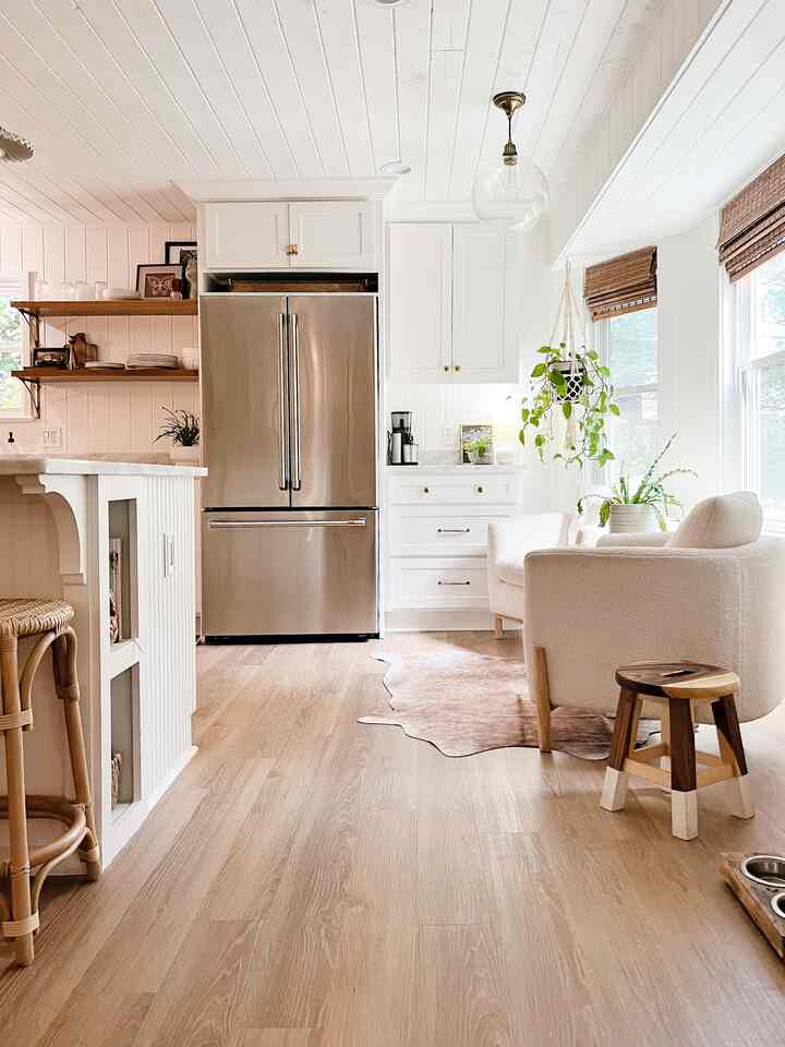 Natural white and brown toned kitchen featuring rattan bar stool, white armchair, and pendant light creating cozy atmosphere