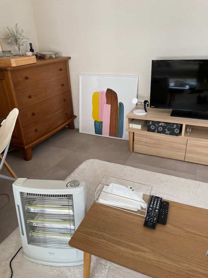 ナチュラルな木目調とホワイトのリビング、暖房器具とポスターが温かい雰囲気を作る空間