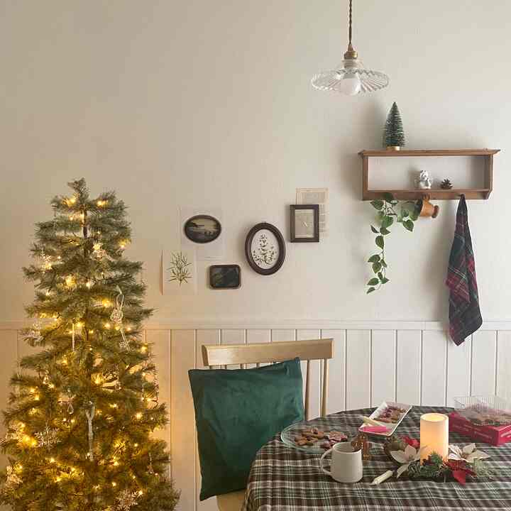 ナチュラルカラーと緑の色調が特徴のダイニング、クリスマスツリーとクッキーが置かれたテーブル、ペンダントライトが温かみのある雰囲気をつくるインテリア