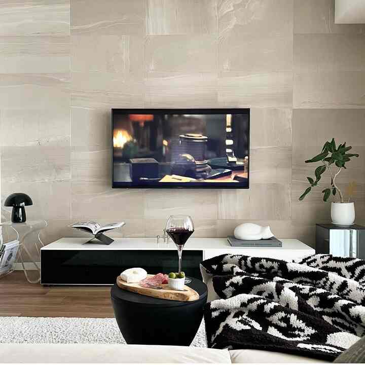 Modern living room in beige and black tones featuring a white TV stand and black coffee table with a stylish atmosphere
