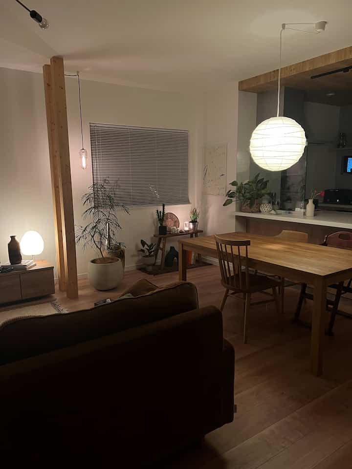 温かみのあるブラウンとホワイトの色調のダイニング、木製のテーブルとソファ、落ち着いた照明が印象的な空間