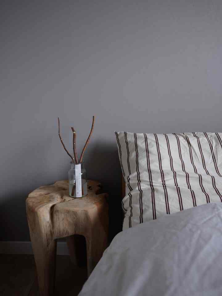 木目調と白色が調和した寝室、ナチュラルなディフューザーと枕が居心地の良い雰囲気を醸し出す空間