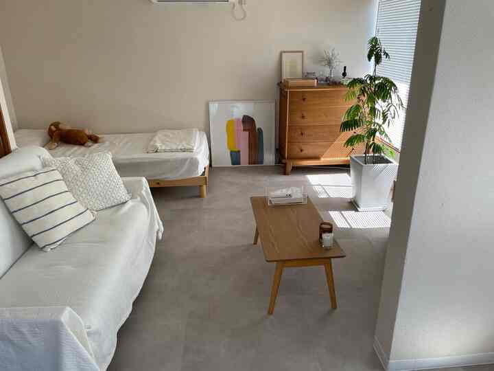 明るい色調のワンルーム寝室、木製家具と植物が配置されたシンプルでナチュラルなインテリア