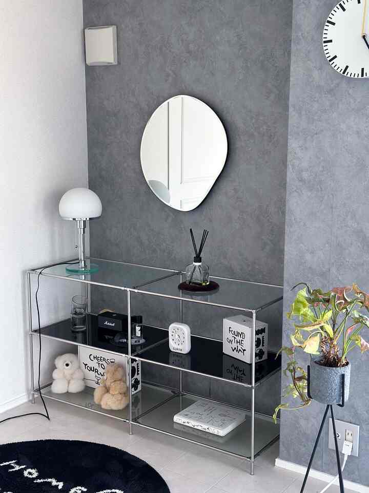 グレーのテクスチャー壁と透明なガラスのモジュラー棚が配置されたモダンなコーナー収納空間