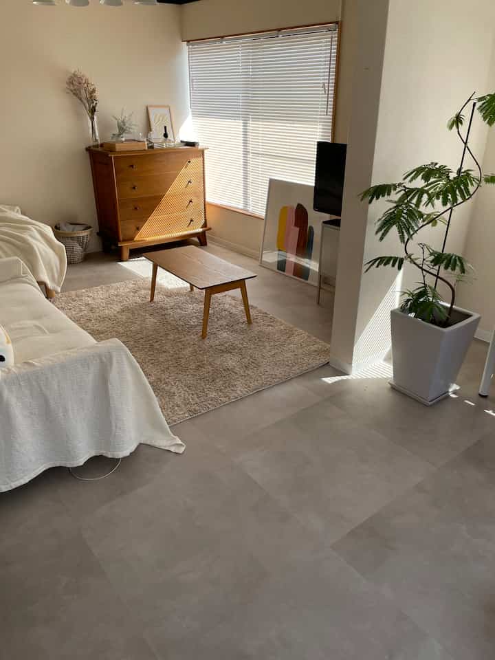 ナチュラルな色調のリビング、白いソファと茶色の木製家具が配置された清潔で温かみのある空間