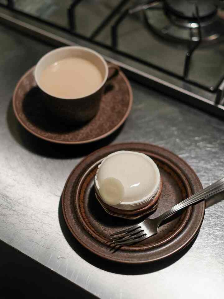 ブラウンの食器とコーヒーが置かれたステンレスの調理台がある落ち着いたキッチンの雰囲気