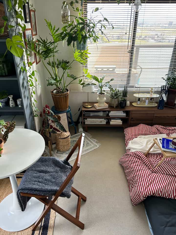 ナチュラルと木目調の色合いが調和した狭いワンルームの寝室、豊富な植物が配置された雰囲気のある空間