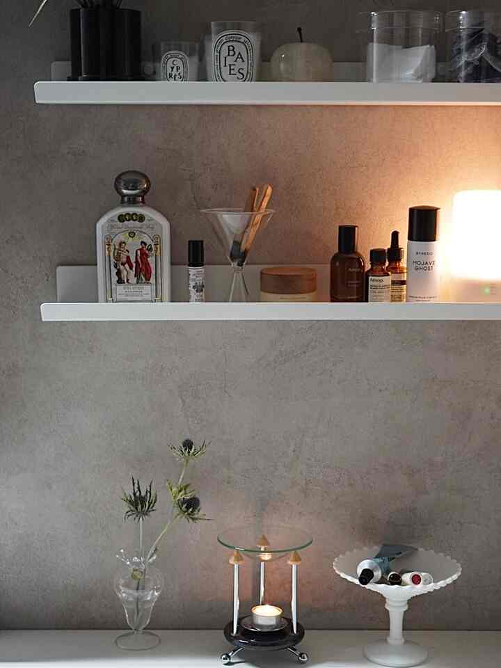 ナチュラルな色調の壁と白い棚が配置されたバスルーム、ヴィンテージのキャンドルバーナーやディフューザー、花瓶がある雰囲気の良いインテリア