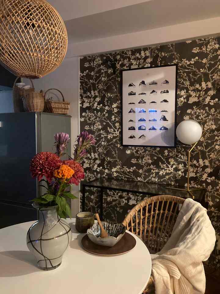 ナチュラルトーンのダイニングルーム、華やかな花瓶とラタンチェアが配置された印象的な空間