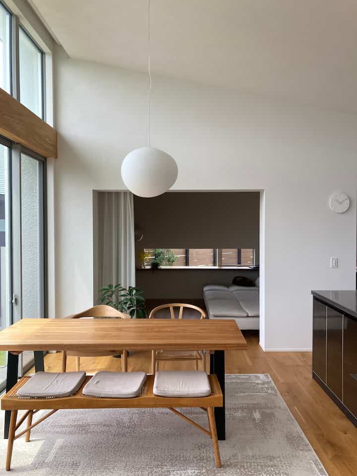 ナチュラルな色調のリビング兼ダイニングルーム、木製のダイニングテーブルとベンチが配置された明るく清潔感のあるインテリア