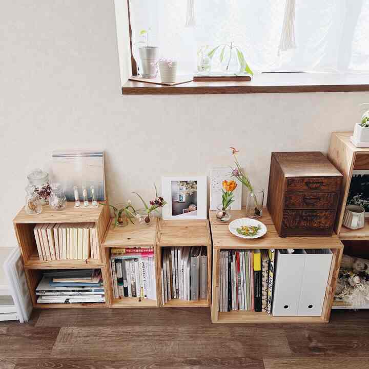 ナチュラルカラーと木目調のワンルーム、花瓶と本棚が配置された雰囲気のあるインテリア