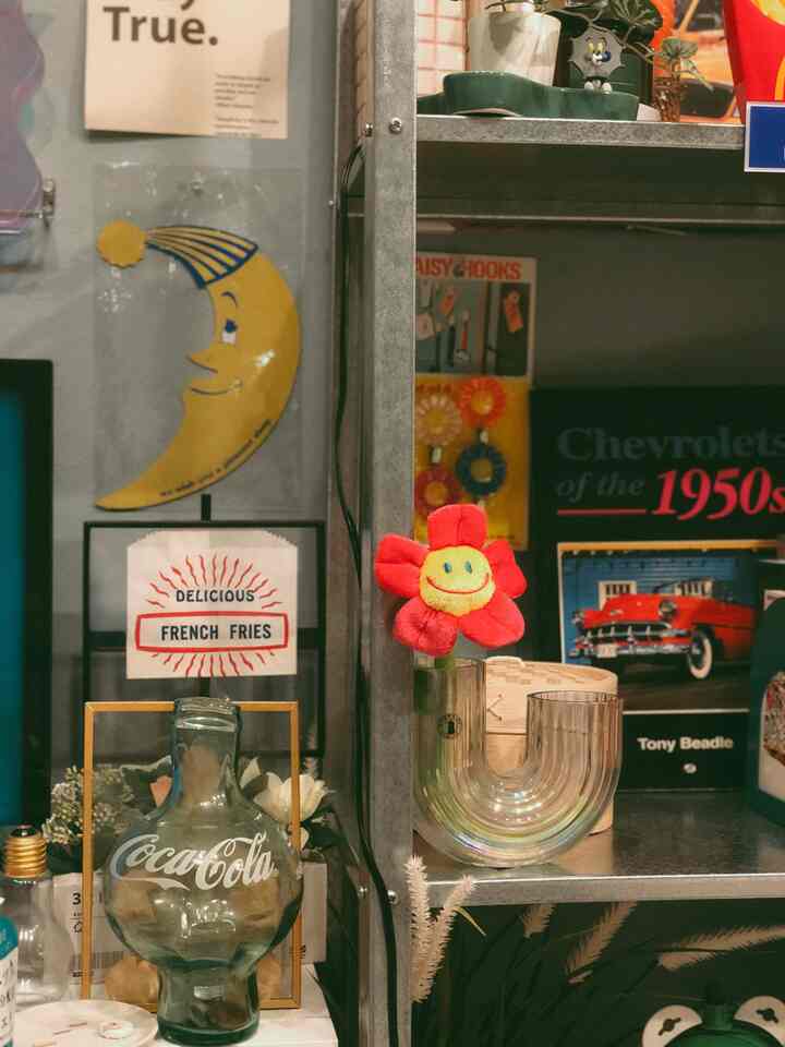 グレーの金属棚に赤い花のオーナメントと透明な花瓶が配置されたレトロなインテリア