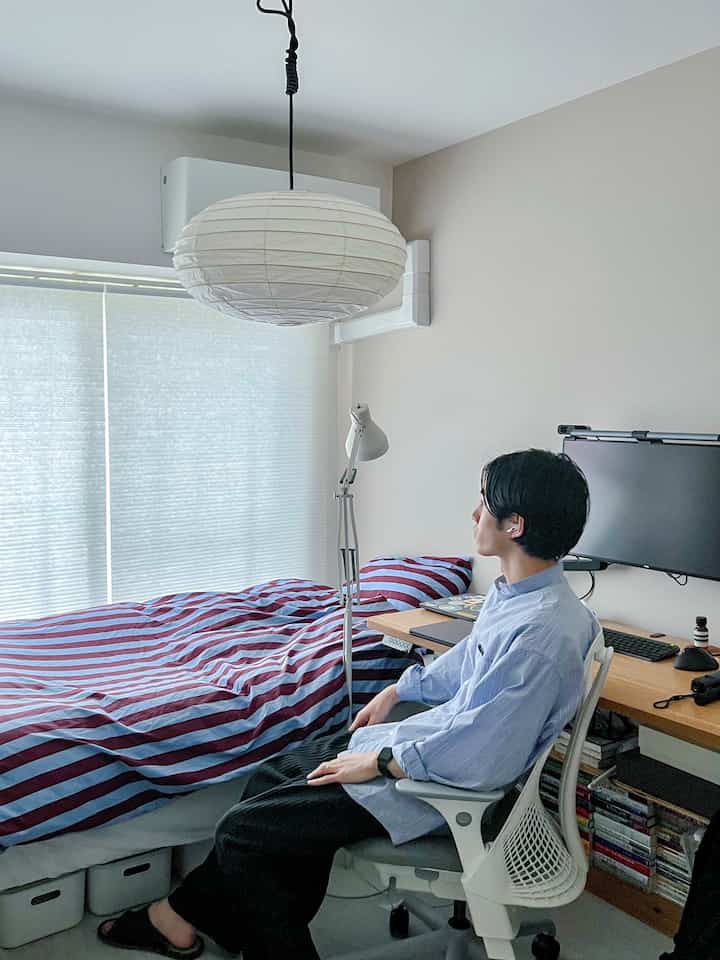 Bright white and beige bedroom featuring red striped duvet cover and modern home office, cozy space for a single occupant