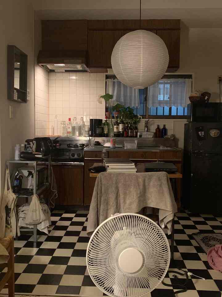 ヴィンテージ調の小さなワンルームキッチン、チェッカーボードの床とデスクが配置された居心地の良い空間