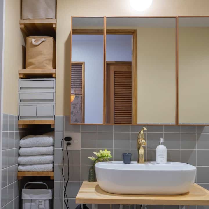 ナチュラルカラーとグレー調のバスルーム、隙間収納と無印良品の引き出しが配置された清潔感のあるインテリア