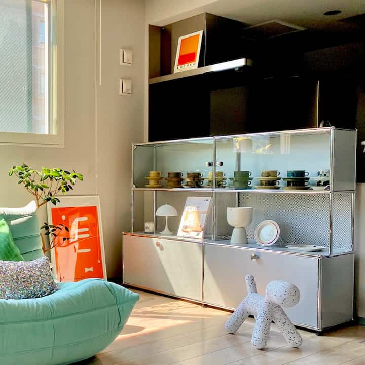 白とミントの色調のリビング、USMサイドボードとソファ、植物が配置された温かみのあるインテリア