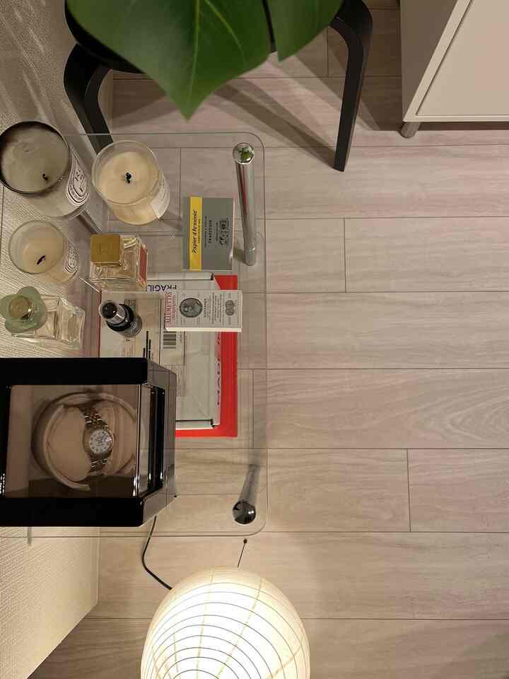 Minimal style living room with white-toned flooring and transparent glass table featuring candles and decor items