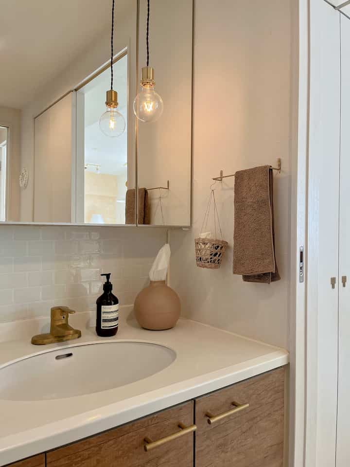 White and brown toned bathroom with wooden vanity and golden towel rack creating a clean and natural atmosphere