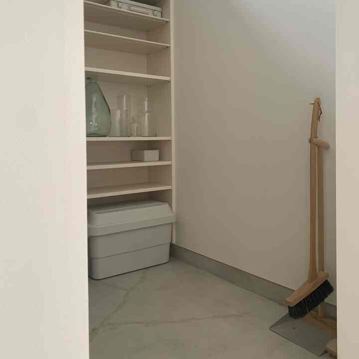 ホワイトトーンの玄関、開放的なシューズラックと収納ボックスが配置されたミニマルで抜け感のある空間