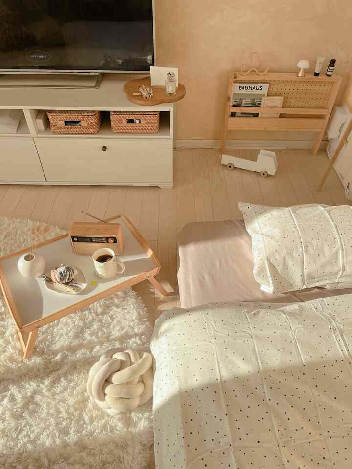 Cozy studio apartment living room in warm beige tones featuring a mattress and natural wood furniture