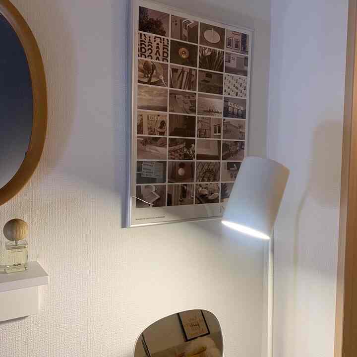 ホワイトトーンのリビング、A2サイズのシルバーアルミフレームのポスターとシンプルなフロアランプが配置された印象的な空間