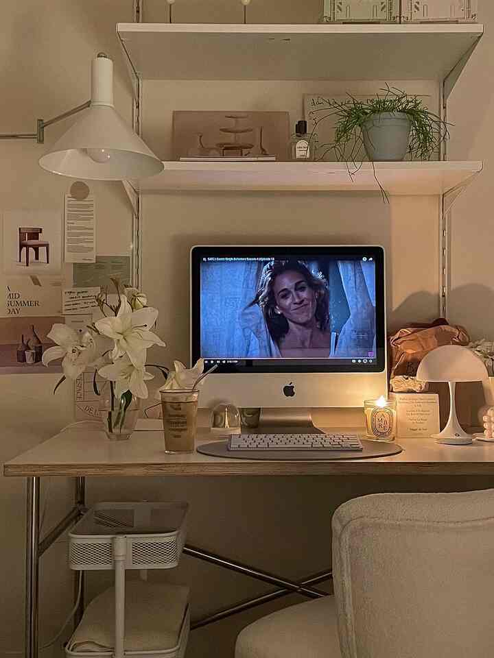 White and natural toned home office featuring a desk with BOAXEL shelf, candle, coffee glass, and warm lighting