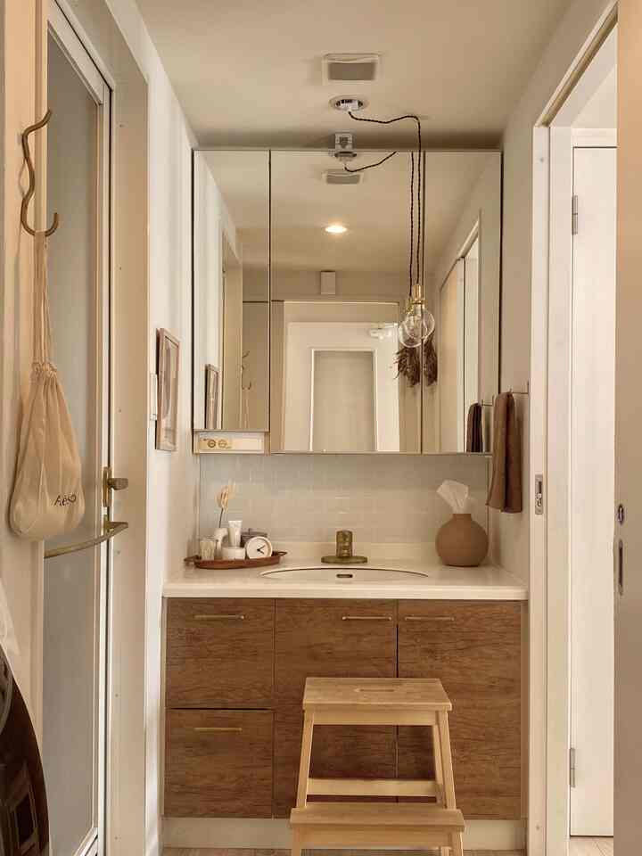 White and wood tone restroom featuring gold-accented sink and towel rack, creating a warm and cozy atmosphere
