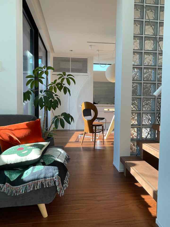 ブラウンの木目調フローリングと白い壁のナチュラルモダンなリビングダイニング、ソファとダイニングチェアが配置された落ち着いた空間