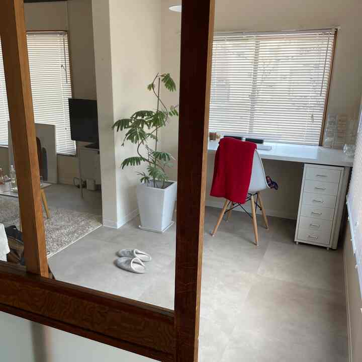 A small home office with white and brown tones featuring a desk and blinds in a simple, natural interior