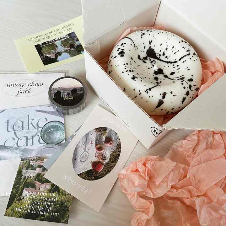 ホワイト背景にヴィンテージポスターと黒い模様のキャンドルが置かれた韓国風の雰囲気あるインテリア