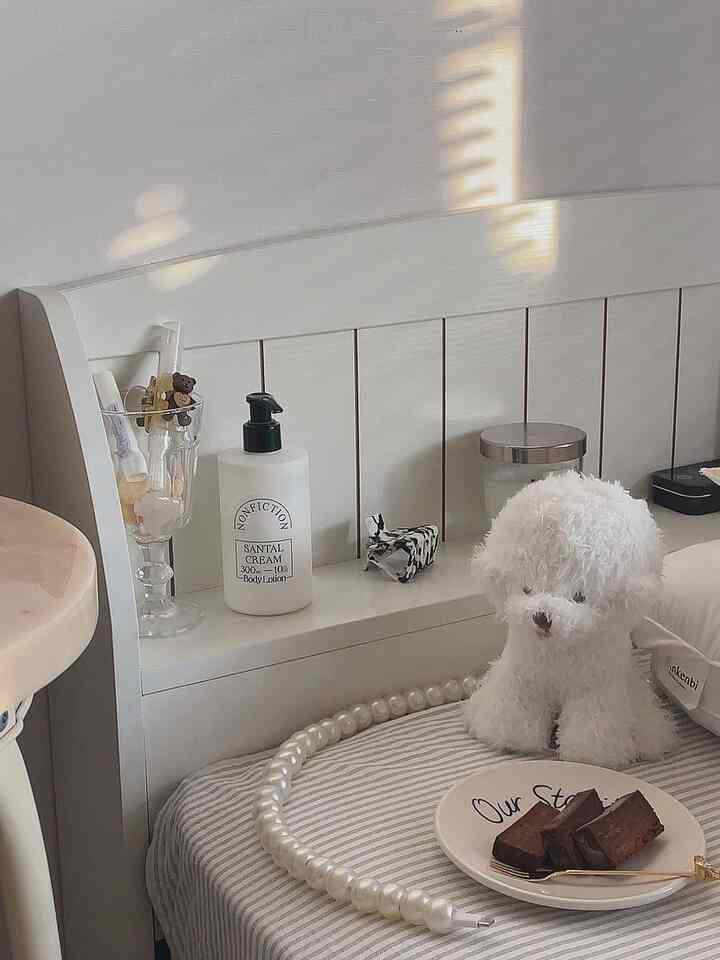 明るいホワイトトーンの寝室、シンプルなベッドとかわいい犬のぬいぐるみがある温かな空間