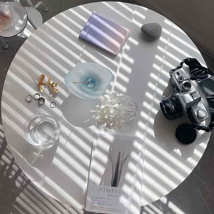 Bright and clean cafe-style space featuring a white round table with a vase of flowers and vintage camera
