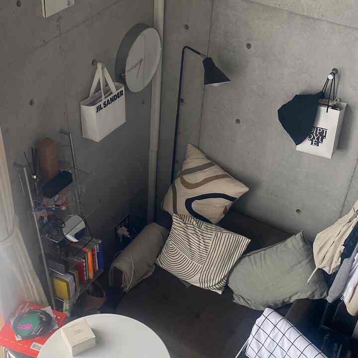 ライトグレーのコンクリート壁とダークブラウンの1人用ソファベッドが配置されたモダンなリビング空間。